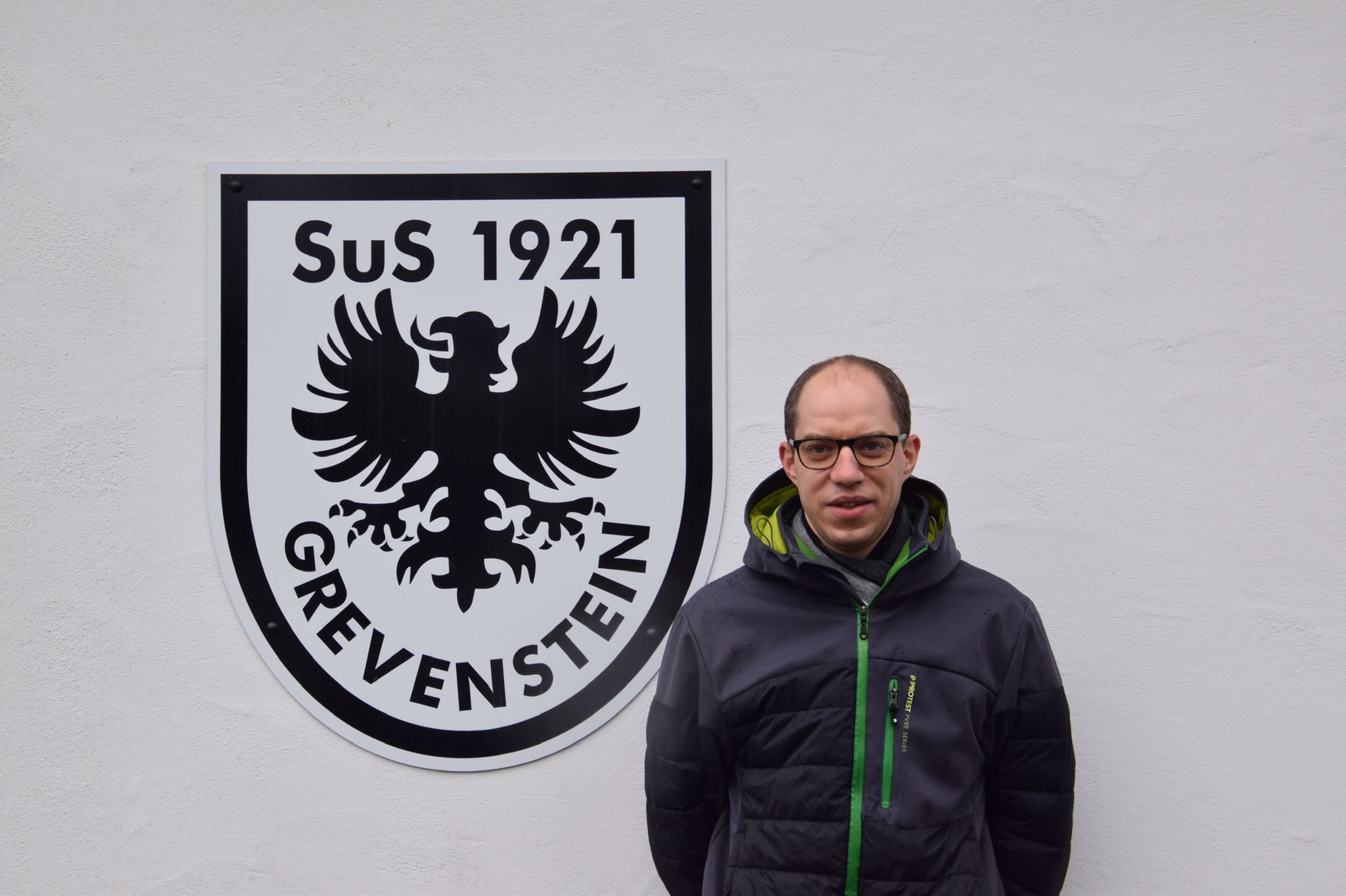 Sebastian Schulte vor dem SuS Grevenstein-Wappen am Sportheim