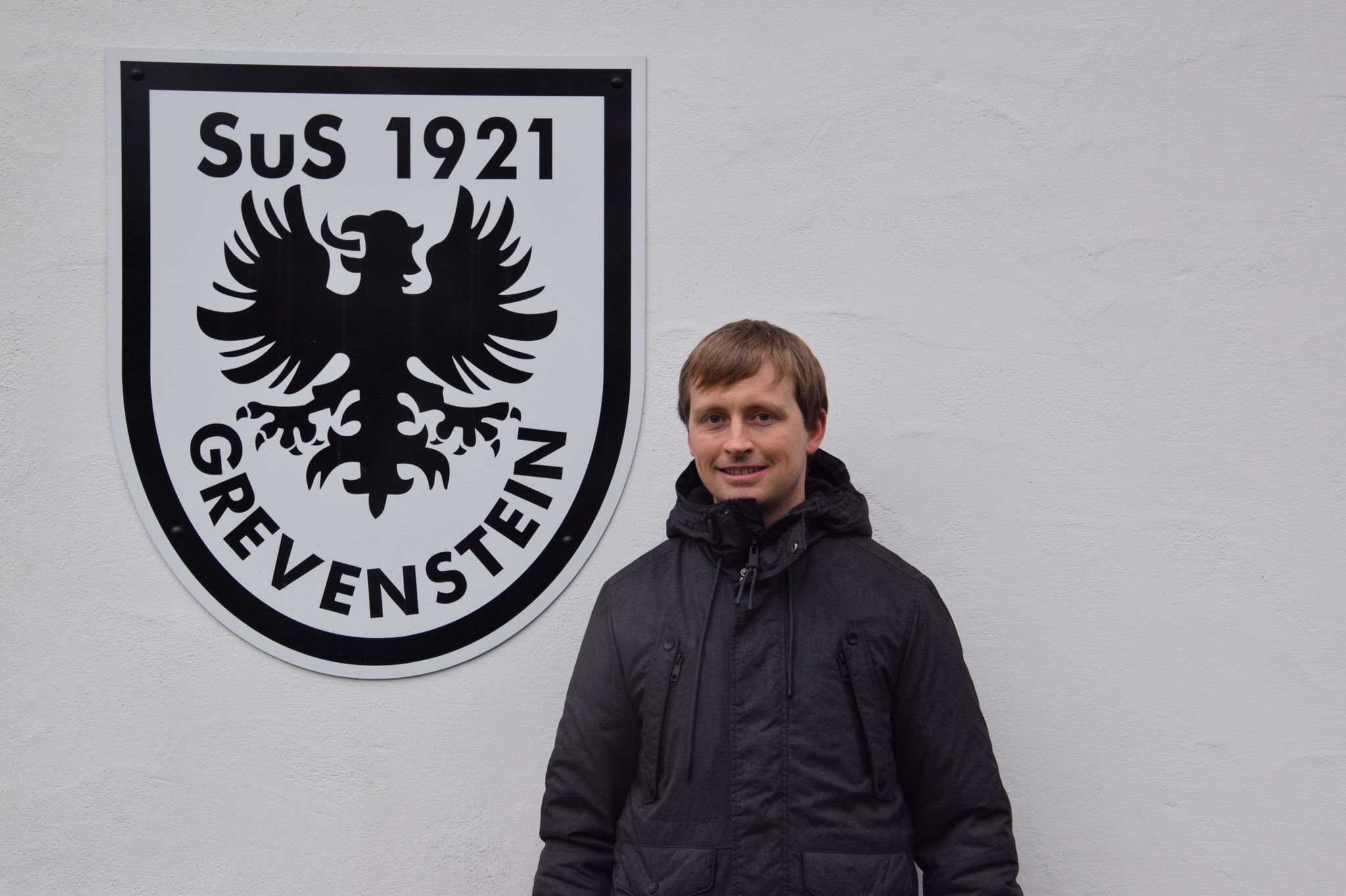 Stefan Kramer vor dem SuS Grevenstein-Wappen am Sportheim