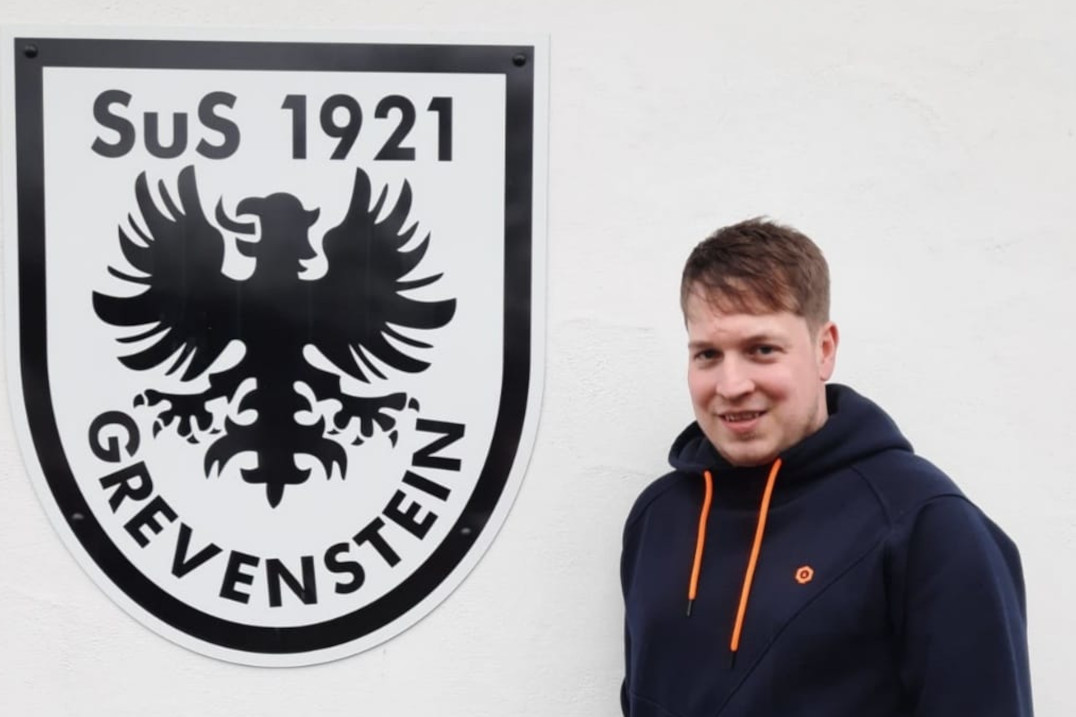 Michael Baumhöfer vor dem SuS Grevenstein-Wappen am Sportheim