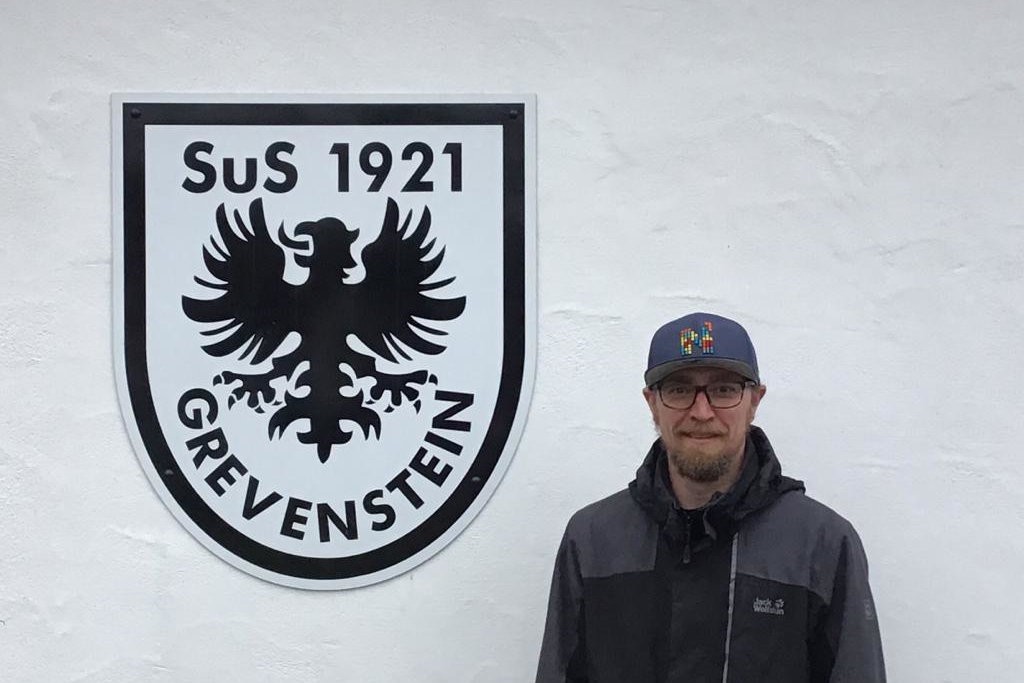 Axel Müller vor dem SuS Grevenstein-Wappen am Sportheim